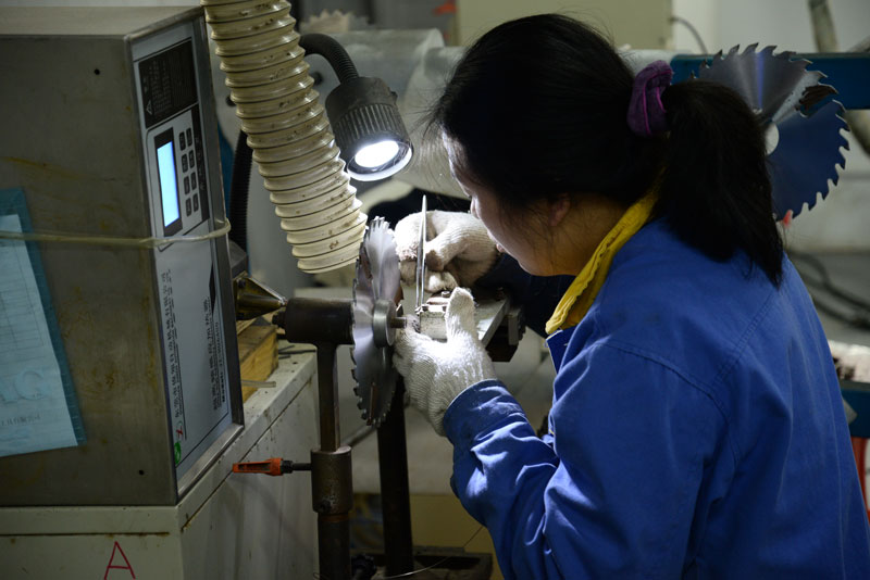 新型圆木多片锯合金锯片生产车间工作人员正在对合金锯片焊接刮刀